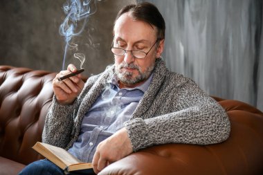 Evde puro okuma kitabı ile Yakışıklı olgun adam