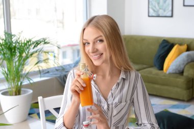 Güzel genç bayan evde taze meyve suyu içiyor.
