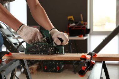 Atölyede elektrikli planör kullanan erkek marangoz