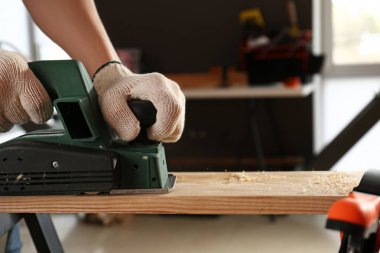 Atölyede elektrikli planör kullanan erkek marangoz
