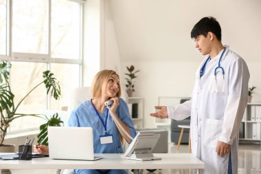 Klinikte çalışan erkek doktor ve kadın tıbbi asistan