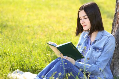 Parkta kitap okuyan güzel genç bir kadın.