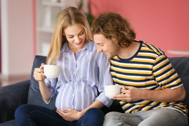 Mutlu genç hamile çift evde çay içme