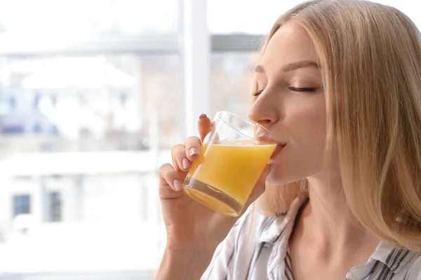 Beautiful young woman drinking fresh juice at home — Stock Photo, Image