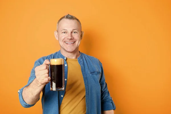 Happy middle-aged man with glass of beer on color background — Stock Photo, Image