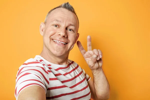 Happy middle-aged man taking selfie on color background — Stock Photo, Image