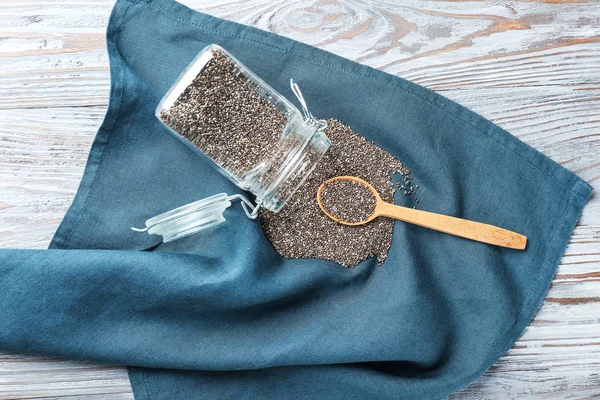 Colher e jarra com sementes de chia na mesa — Fotografia de Stock