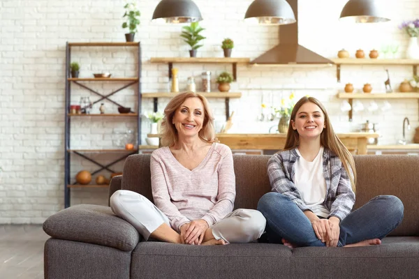 Feliz madre e hija sentadas en el sofá en casa — Foto de Stock