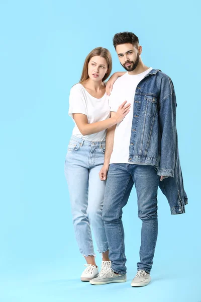 Elegante pareja joven en ropa vaqueros sobre fondo de color — Foto de Stock