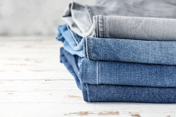 Pila de ropa vaqueros en la mesa de madera, primer plano — Foto de Stock