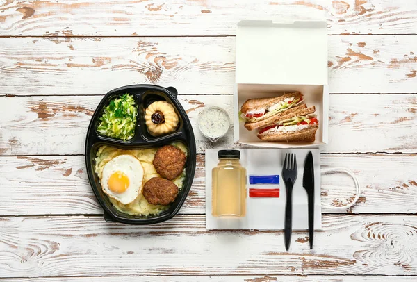 Container met heerlijk eten en drinken op witte houten achtergrond — Stockfoto