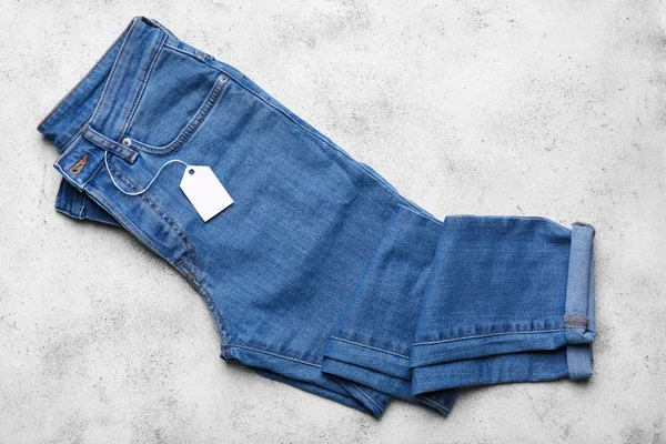 Calça jeans com etiqueta de compras no fundo claro — Fotografia de Stock