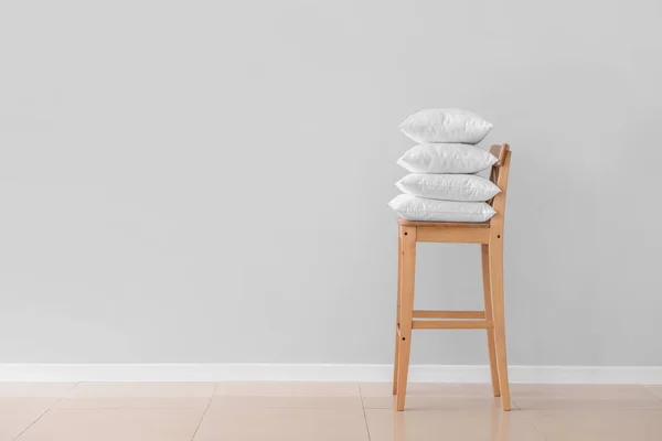 Zachte kussens op stoel tegen lichte muur — Stockfoto