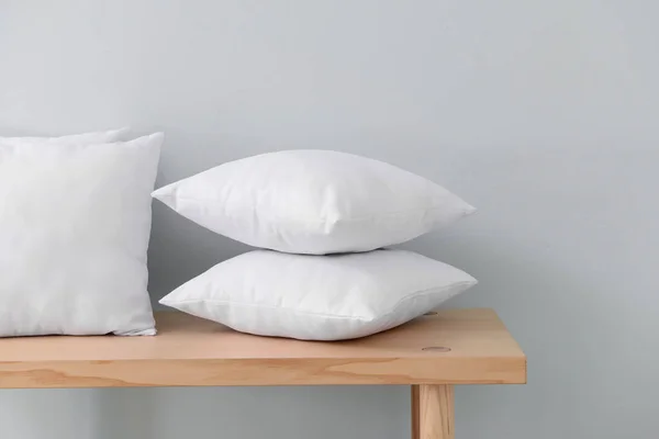 Soft pillows on table against light wall — Stock Photo, Image