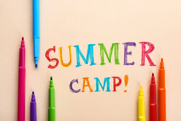 Felt-tip pens and text SUMMER CAMP on color background