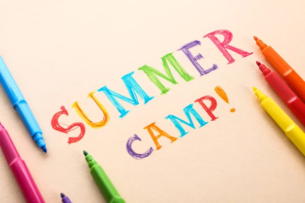 Felt-tip pens and text SUMMER CAMP on color background