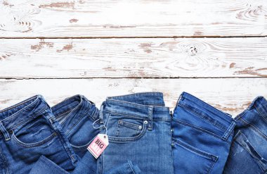 Beyaz ahşap arka plan üzerinde alışveriş etiketi ile farklı kot pantolon