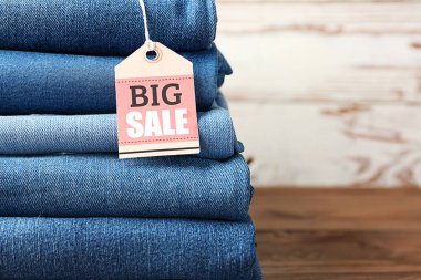 Ahşap masa üzerinde alışveriş etiketi ile farklı kot pantolon Yığını