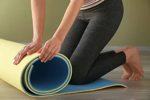 Giovane donna sportiva con stuoia di yoga in palestra — Foto Stock