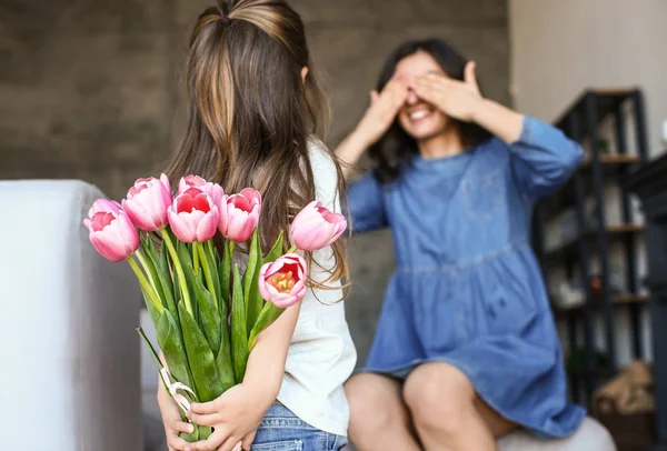 Meisje houdt boeket van bloemen voor moeder achter haar terug thuis — Stockfoto