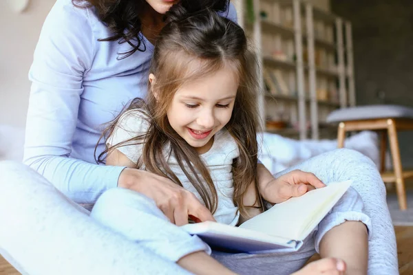 Gelukkig moeder met dochter leesboek thuis — Stockfoto