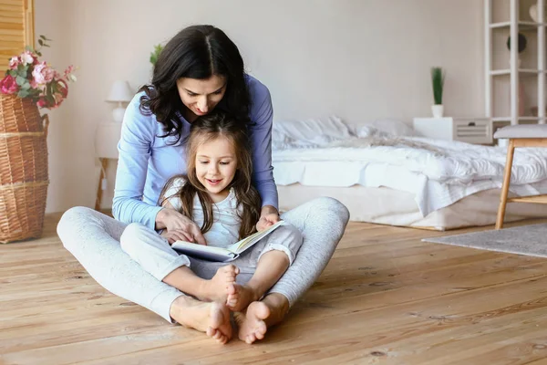 Gelukkig moeder met dochter leesboek thuis — Stockfoto