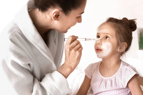 Madre aplicando máscara en la cara de su hija en casa — Foto de Stock