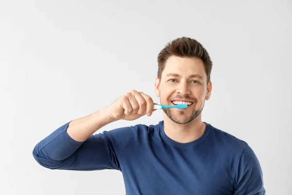 Hombre limpiando dientes sobre fondo claro — Foto de Stock