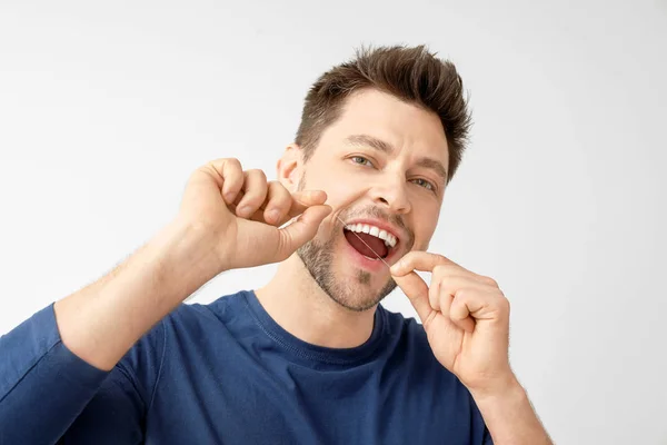 Hombre dientes de hilo dental sobre fondo claro —  Fotos de Stock