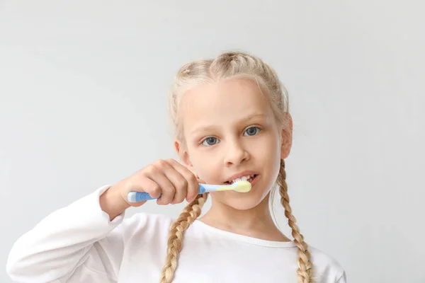 Mała dziewczynka czyszczenia zębów na jasnym tle — Zdjęcie stockowe