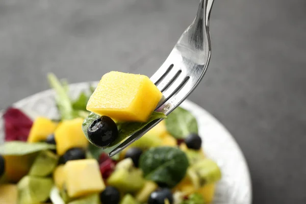 Eating of tasty mango salad, closeup