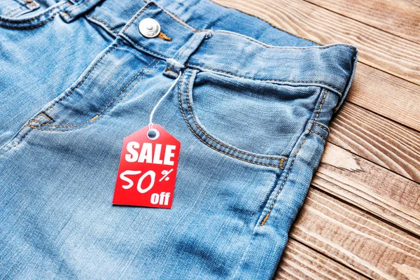 Jeans con estilo con etiqueta sobre fondo de madera, primer plano —  Fotos de Stock