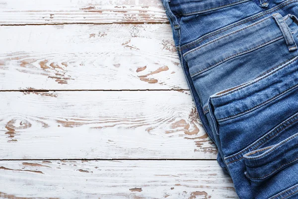 Pantaloni jeans diversi su sfondo bianco in legno — Foto Stock