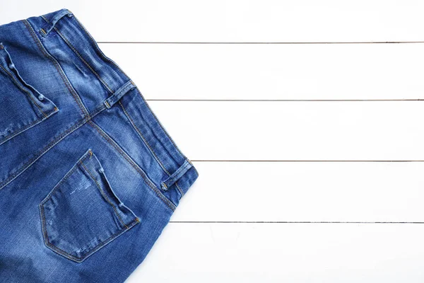 Calça jeans elegante na mesa de madeira branca — Fotografia de Stock