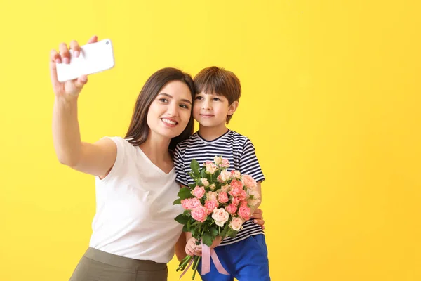 Happy mother and son taking selfie on color background — Stock Photo, Image