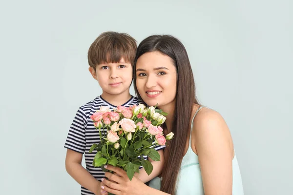 Счастливая мать и сын с букетом цветов на светлом фоне — стоковое фото