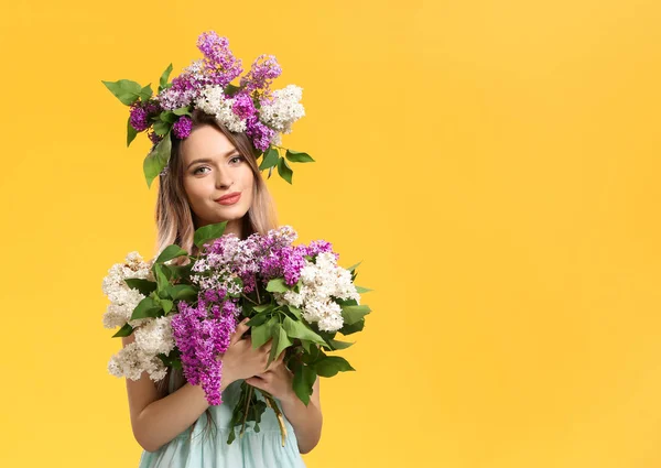 Beautiful young woman with lilac flowers on color background — Stok fotoğraf