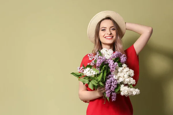 色の背景にライラックの花の花束を持つ美しい若い女性 — ストック写真