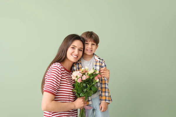 Szczęśliwy matka i syn z bukiet kwiatów na kolorowym tle — Zdjęcie stockowe