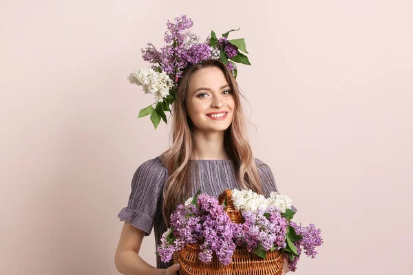 Beautiful young woman with lilac flowers on light background — Stock Photo, Image