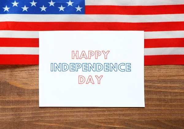 Flagga av Amerikas förenta stater och kort med text lycklig självständighetsdag på trä bakgrund — Stockfoto