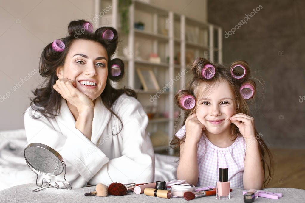 Mother with cute daughter doing makeup at home