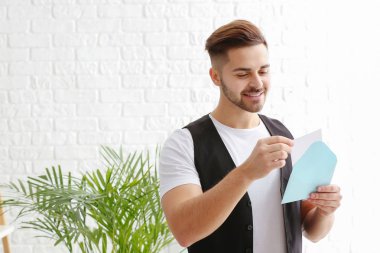 Young man opening envelope with invitation at home