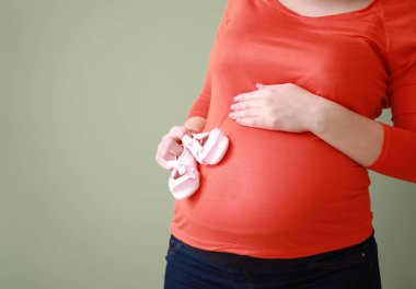 Renkli arka planda bebek booties ile güzel hamile kadın