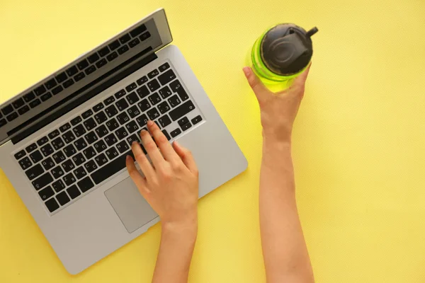 Жіночі руки з ноутбуком і пляшкою води на йога килим. Концепція балансу між відпочинком і роботою — стокове фото