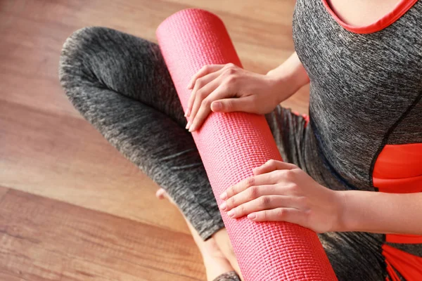 Jovem mulher esportiva com tapete de ioga no ginásio, close-up — Fotografia de Stock