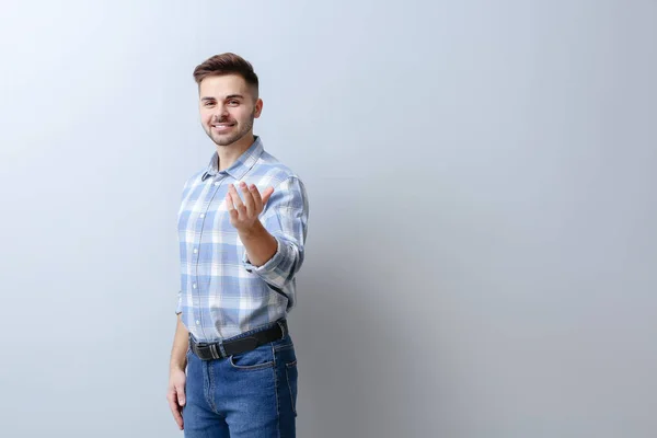 Hombre guapo mostrando "ven aquí" gesto sobre fondo claro —  Fotos de Stock