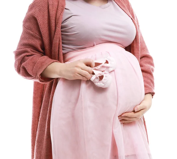 Krásná těhotná žena s dětskými botičky na bílém pozadí — Stock fotografie