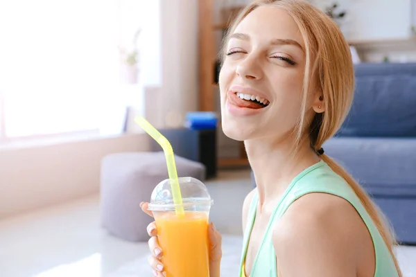 Sporty young woman drinking fresh juice at home — Stock Photo, Image