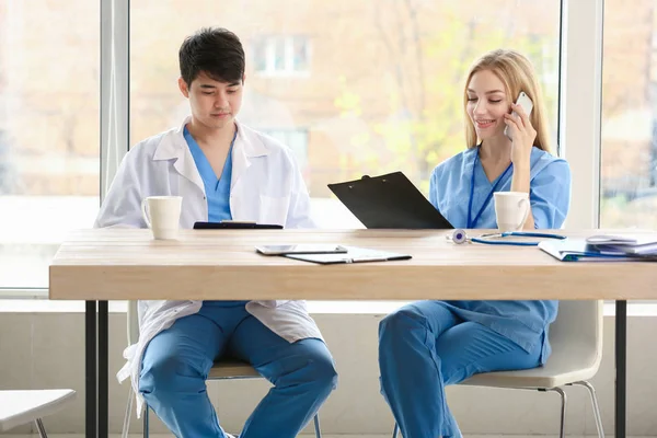 Médico masculino e assistente médico feminino sentados à mesa na clínica — Fotografia de Stock